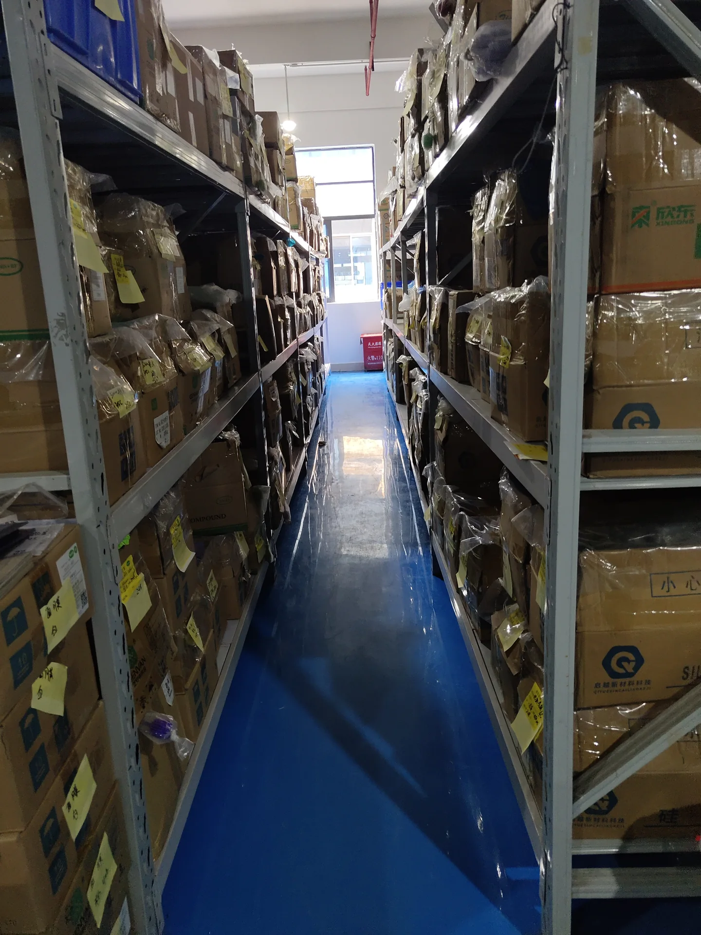 Shelved cartons and stored materials along a factory aisle
